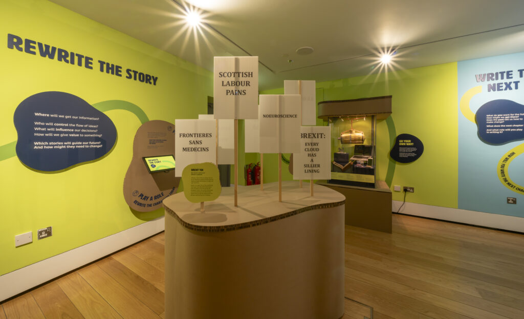 Section of the gallery with signs and a case in the background.